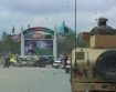 American forces maneuver in front of a sign honoring Afghan hero Massoud, with the historic Blue Mosque in the background.