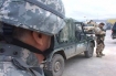 An American soldier looks toward in International Security Assistance Forces vehicle and a British soldier.