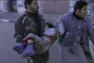 Men carry child from a school hit by air strike in Gaza.