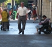 Downtown Portland, Oregon, a seemingly affluent man passing between a homeless woman and a handicapped woman slumped in a wheelchair