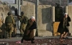 Palestinian women hurry past IDF soldiers in their occupied nation