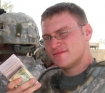 Lt. Brian Reynolds, an officer with the 101st Airborne in Iraq last summer, holds money that will be paid to Sunni militia members.  Salem-News.com photo by Tim King