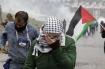 A Palestinian woman shields her eyes from Israeli tear gas, used by the IDF to routinely attack non-violent protestors.