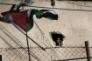 A Palestinian woman peers from a hole at a house near a UN school