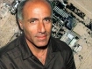 Mordechai Vanunu. In the back, a satellite image of the production centre of military grade plutonium of Dimona, Israel.