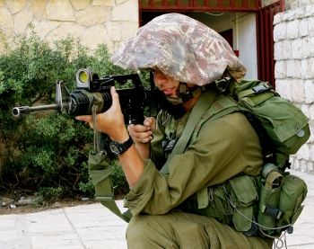 Israeli soldier trains his weapon on Palestinian peace protesters on the West Bank.